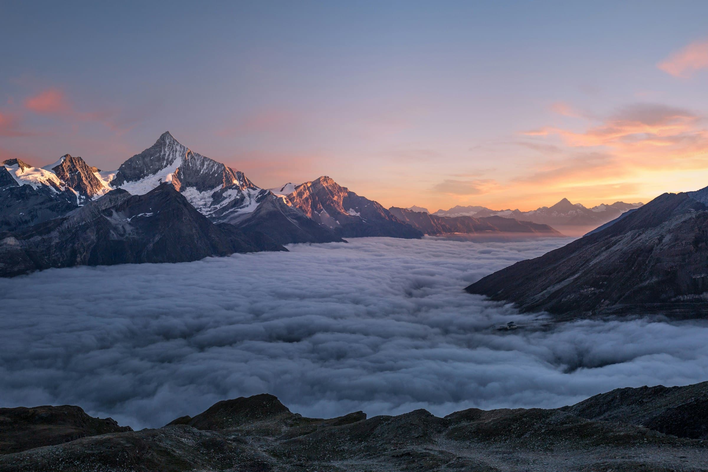 Alpine peaks catching the first light above a valley of cloud